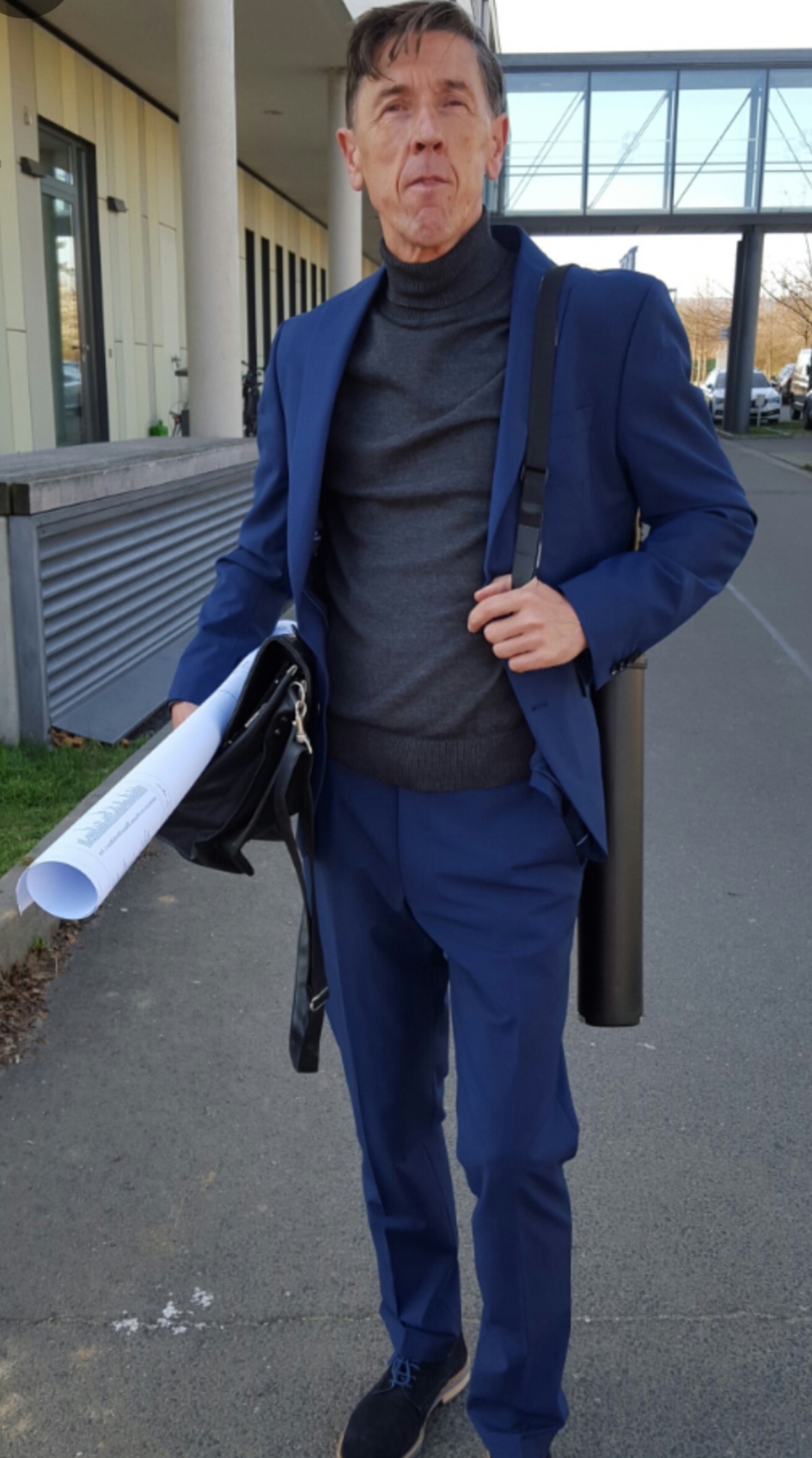Uwe Koczulap im blauen Anzug mit Mappe und Plänen