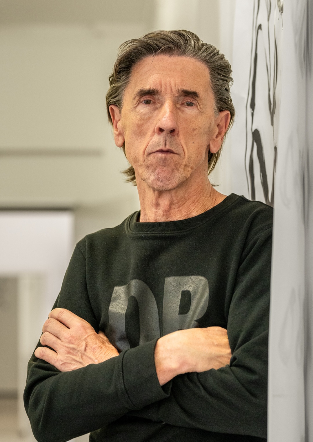 Uwe Koczulap mit verschränkten Armen an einer Wand lehnend